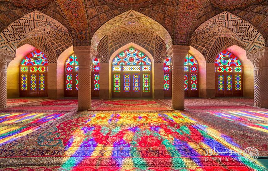 تصویری از فضای داخلی مسجد نصیرالملک شیراز که بازتاب نور از شیشه‌های رنگی مسجد روی فرش دیده می‌شود.